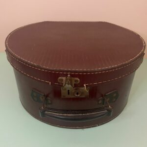 Ancienne boîte à chapeau vintage en simili cuir brun avec poignée et fermeture d’origine. Une pièce rétro pleine de charme pour une décoration authentique et nostalgique.